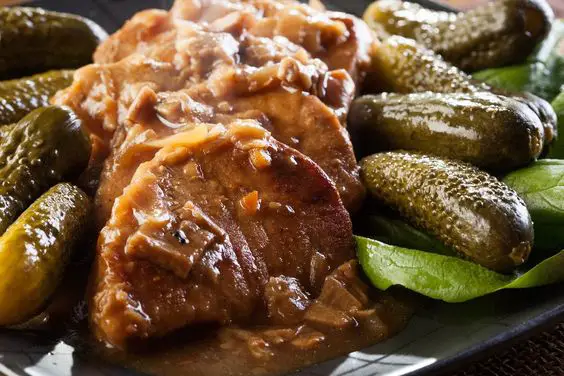 Slow Cooker Pork Roast with Mushrooms sliced on a plate with pickles.