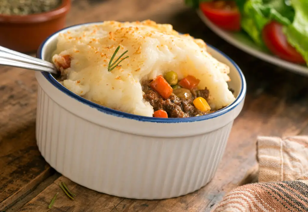 Shepherd's Pie in a blue and white bowl on a wooden table.