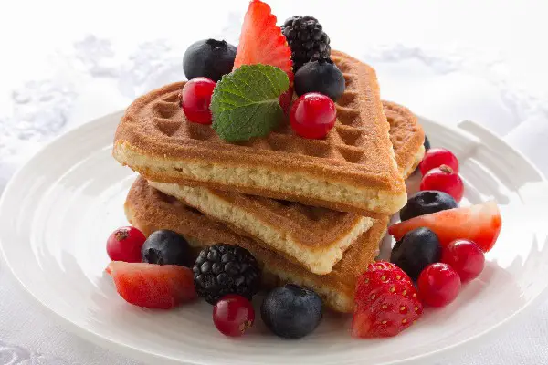 Stack of Whole Grain Waffles on a white plate with berries.