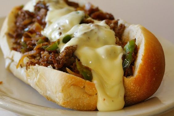 Philly Cheesesteak Sandwich with Peppers and Onions on a white plate.