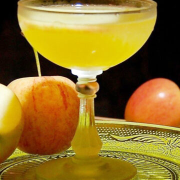 Apple Cider Vodka Martini in a clear glass on a glass plate.