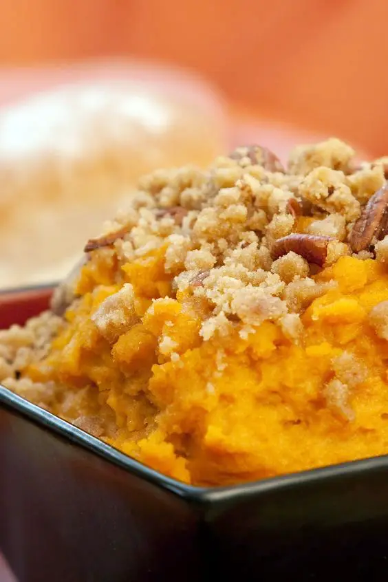 Closeup of Sweet Potato Souffle in a square, brown bowl. Orange out of focus background