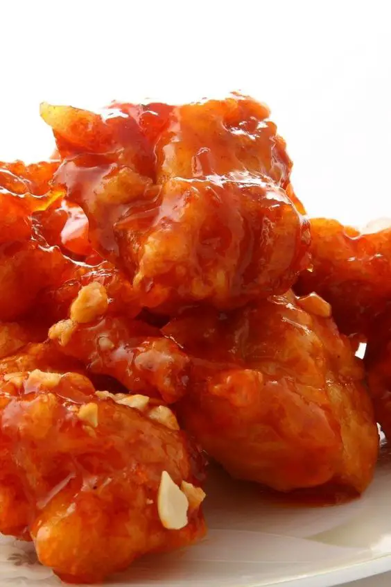 Closeup of Chinese Chicken with Sweet and Sour Sauce on a white plate with a white background.