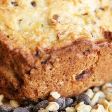 Closeup of zucchini bread surrounded by chocolate chips and chopped walnuts.