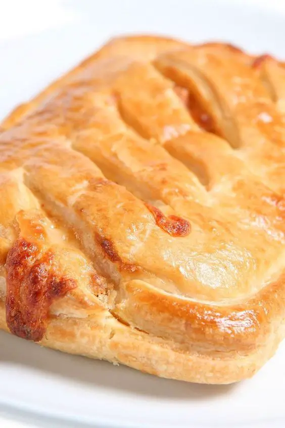 Closeup of a Corn and Ham Turnover on a white plate with a white background.