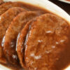 Closeup of Hamburger Patties with Creamy Balsamic Sauce on a white plate.