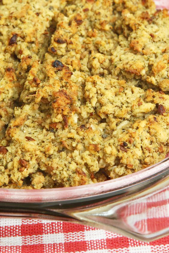 Closeup of Apple and Sausage Stuffing in a glass dish on a red and white tablecloth.
