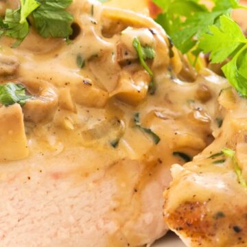 Close-up of Copycat Carrabba’s Chicken Marsala—sliced seared chicken breast topped with creamy Marsala wine mushroom sauce, onions, and parsley, with roasted potato blurred in the background. Italian chicken dinner, creamy mushroom sauce recipe.