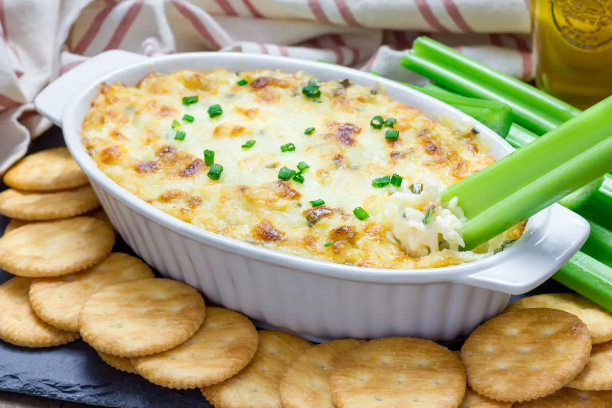 Copycat Joe's Crab Shack Crab Dip in a white casserole dish surrounded by crackers and celery.