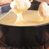 Cheese fondue in black pot.