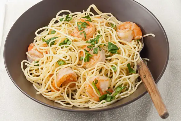Shrimp and Pasta with Lemon Sauce in a brown bowl with a wooded spoon.