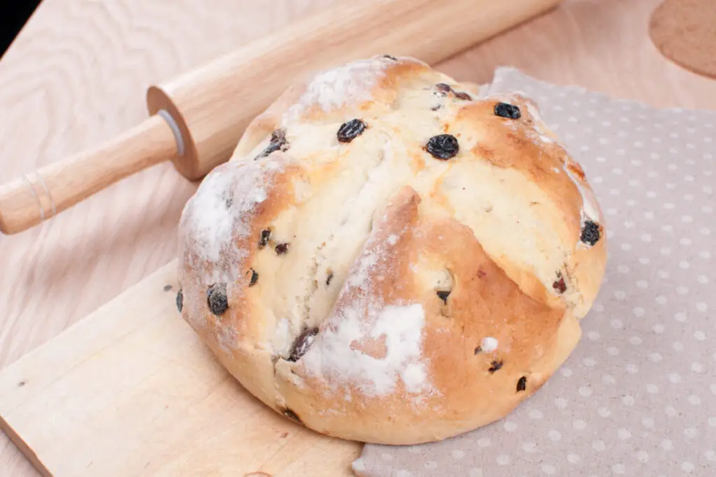  Irish Soda Bread on a wooded surface with a rolling pin next to it.