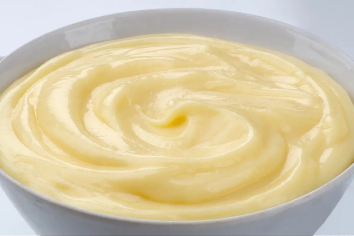 Homemade Vanilla Pudding in a white bowl, sitting on a white surface.