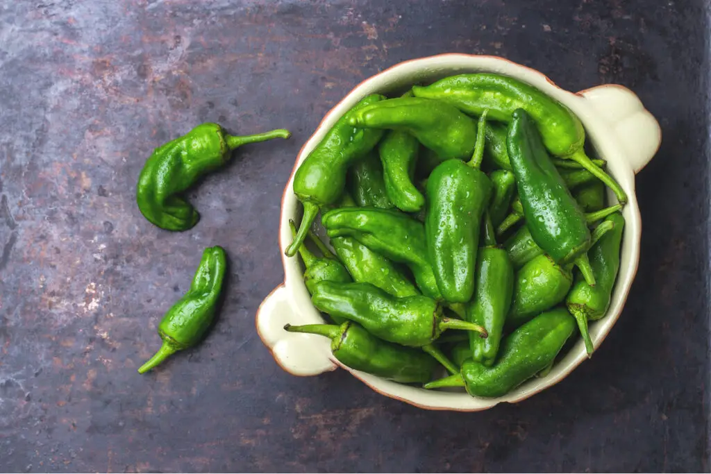Jalapeno peppers in a bowl on a slate surface.