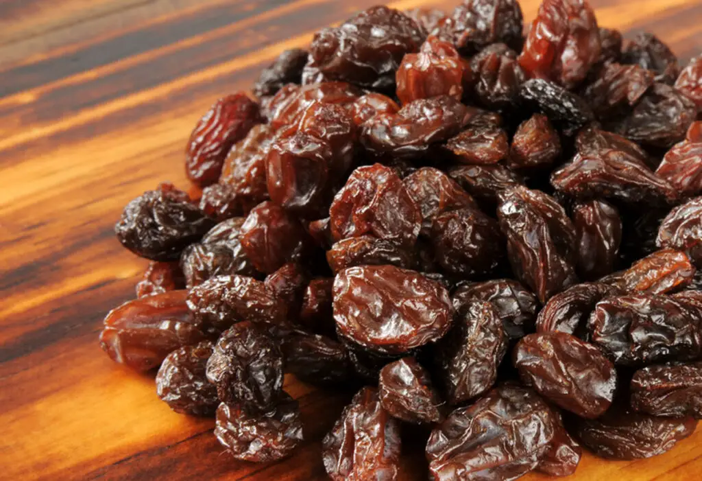 A mound of fresh organic raisins on a cutting board.