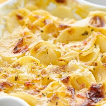 Closeup of Best Au Gratin Scalloped Potatoes in a white casserole dish.