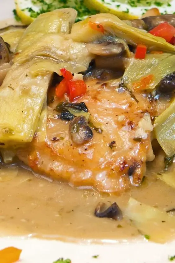 Closeup of Chicken Artichoke and Mushrooms on a white plate.