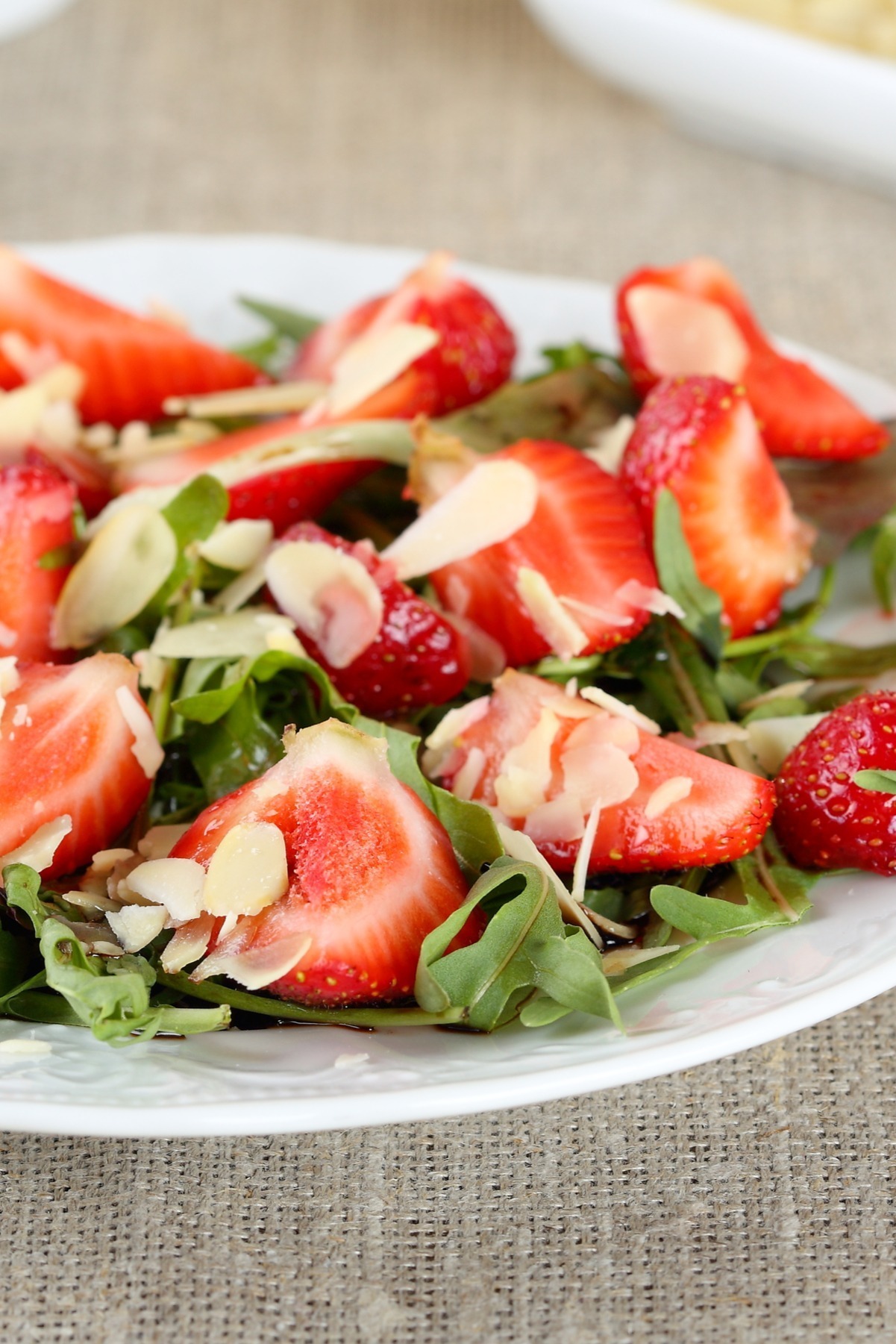 Balsamic Arugula Salad with Strawberries on a white plate.