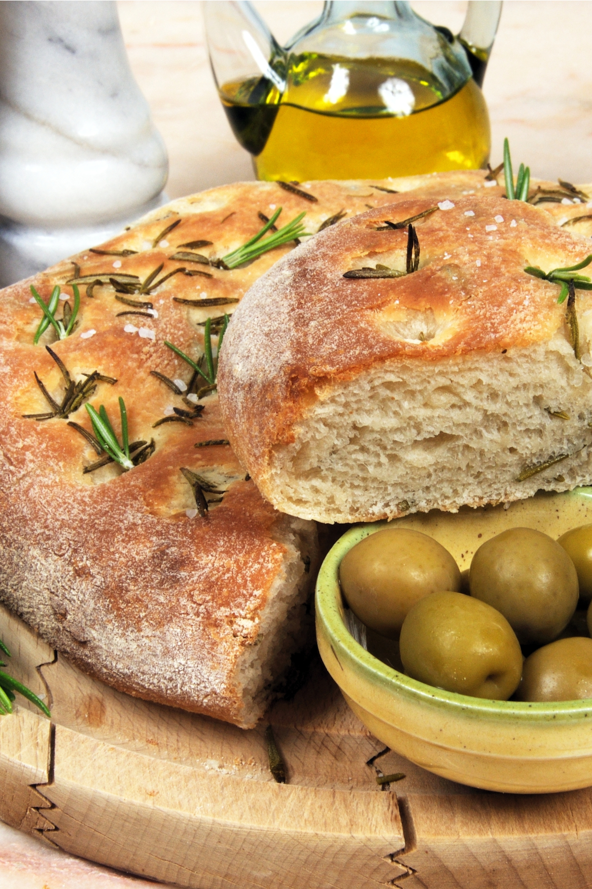 Copycat Rosemary Bread on a cutting board with a small dish of olives.