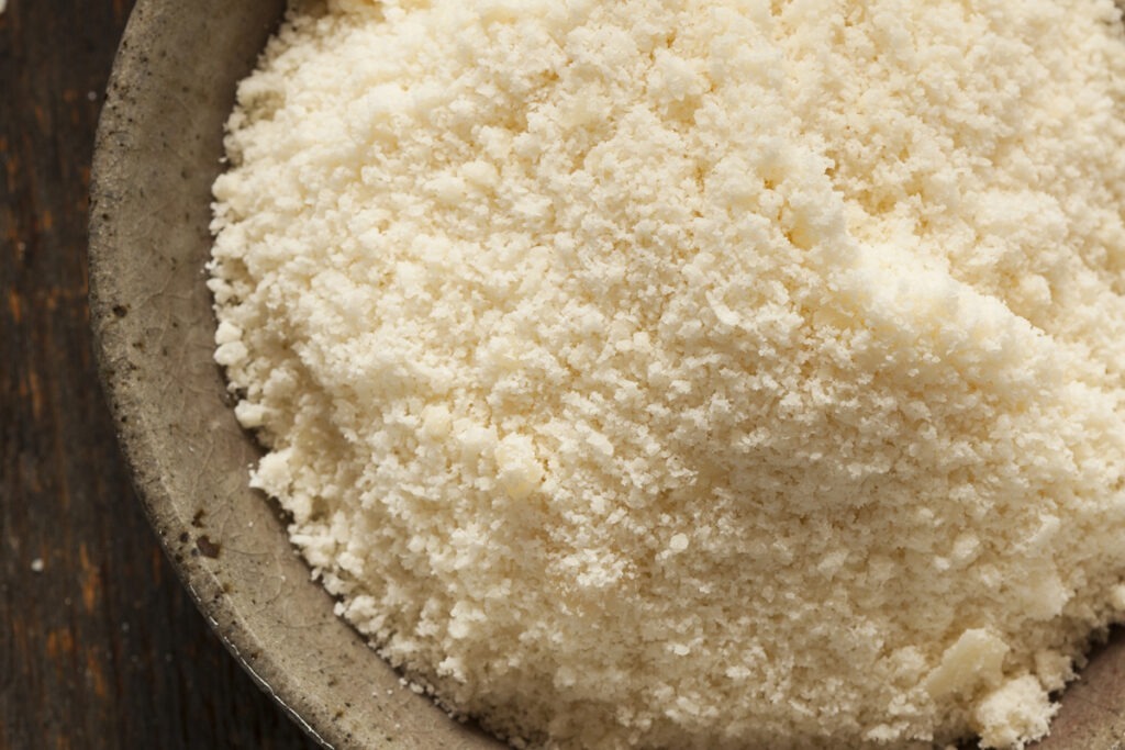 A bowl of grated parmesan cheese in a wooden bowl.