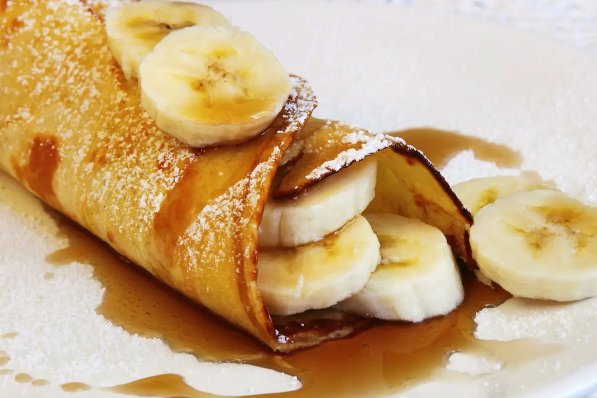 Delectable Banana Stuffed Crepes on a white plate.