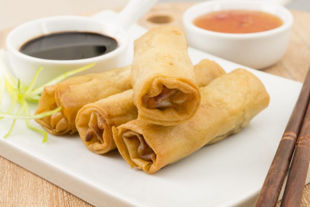 Homemade Beef Egg Rolls on a square, white plate with a small cup of soy sauce.