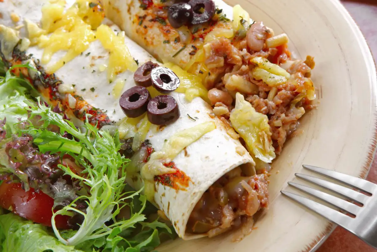 Mouthwatering Homemade Beef Enchiladas on a white plate with a fork.