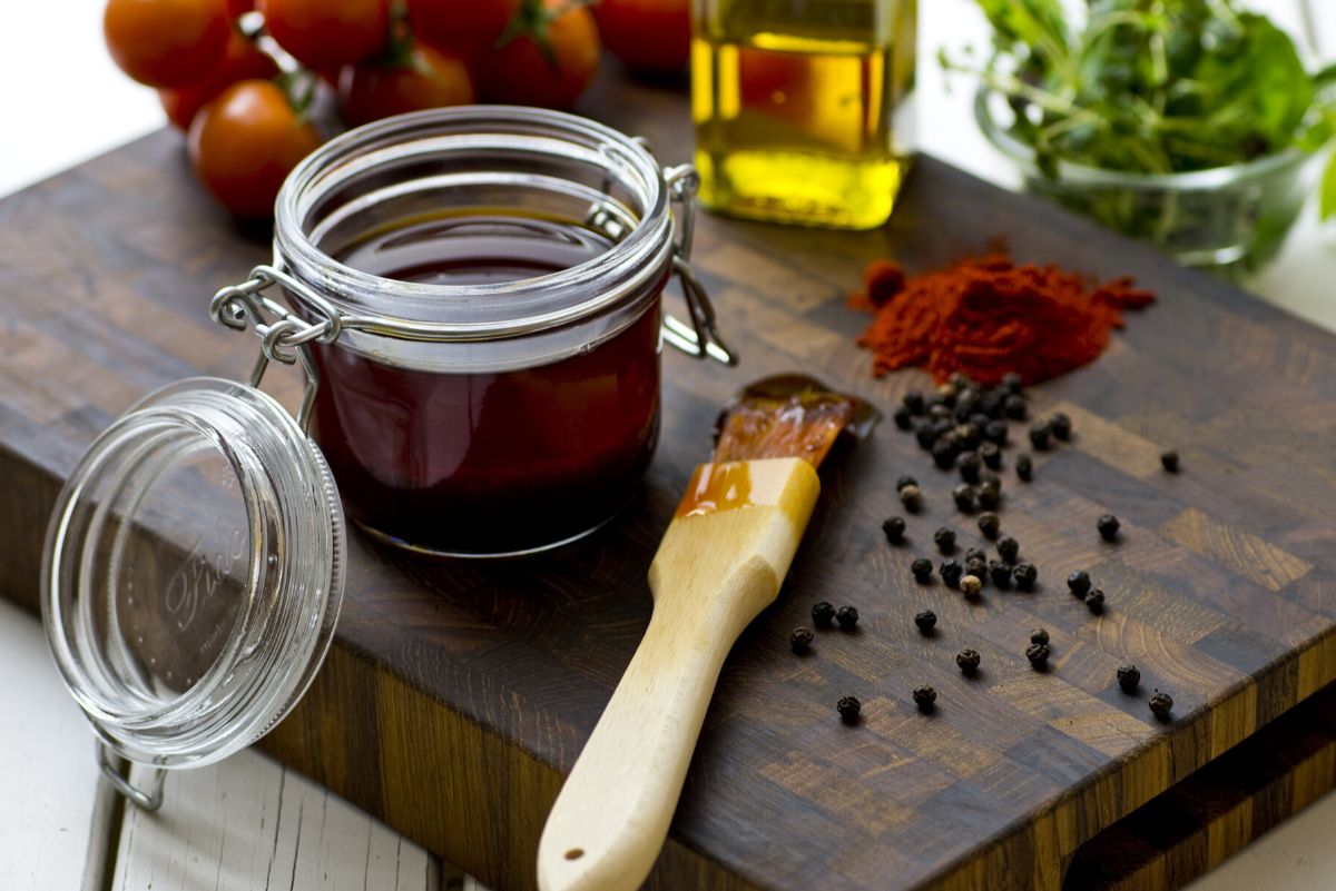 Ultimate Bourbon Barbecue Sauce in a glass jar with a sauce brush next to it.