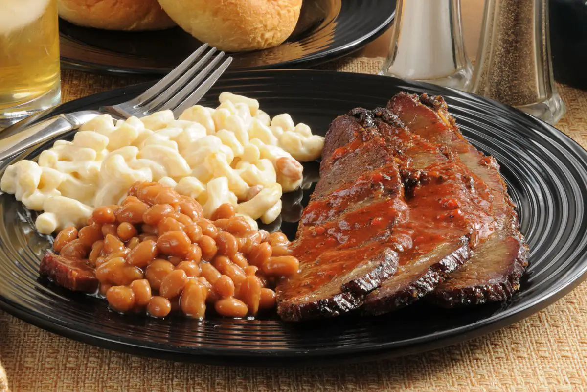Finger-Lickin' Slow Cooker BBQ Beef Brisket on a black plate with baked beans and macaroni and cheese.