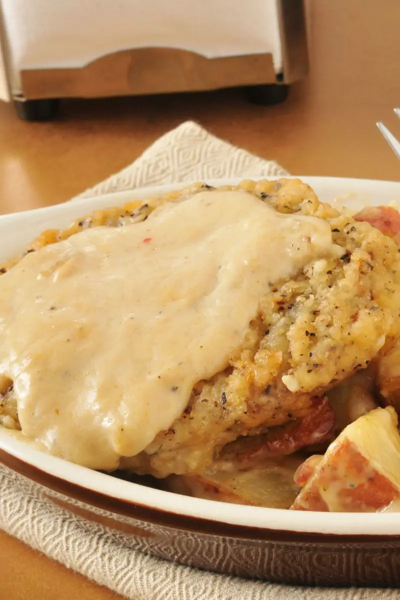 Closeup of Southern-Style Chicken Fried Steak with Cream Gravy on a white plate.