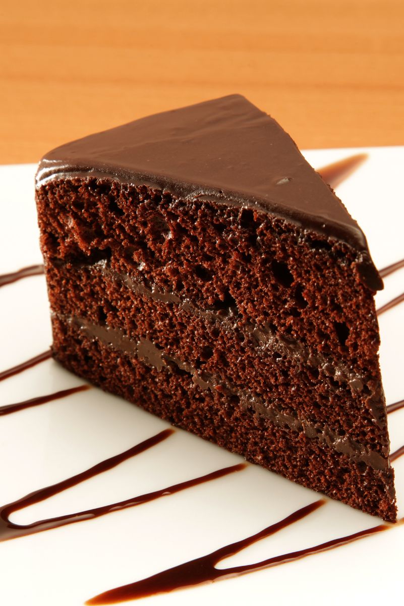 Closeup of a slice of Sinfully Delicious Coffee and Chocolate Cake on a white plate with chocolate drizzle.