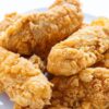 Closeup of Crispy and Delicious Buttermilk Chicken Fingers on a white surface.