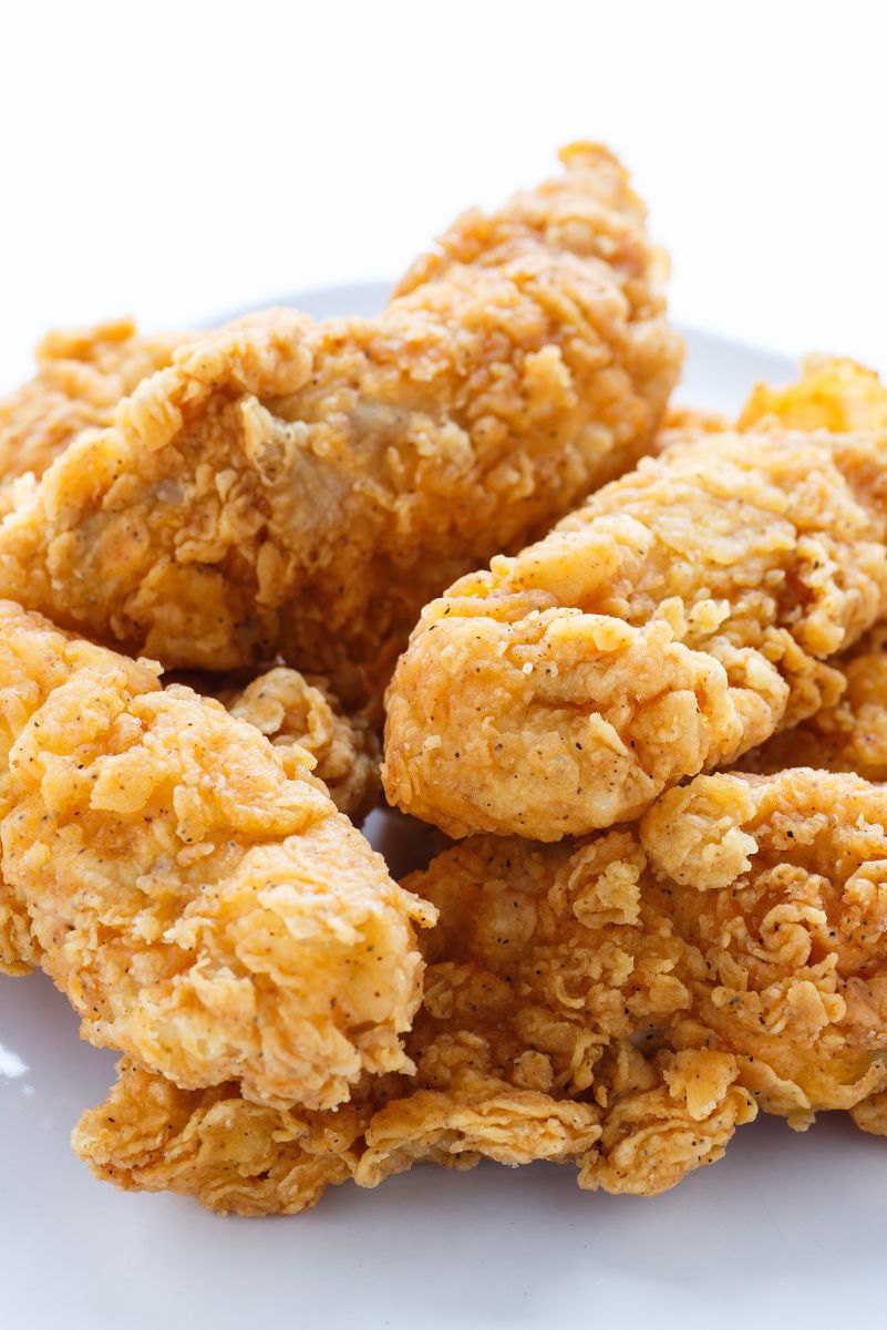 Closeup of Crispy and Delicious Buttermilk Chicken Fingers on a white surface.