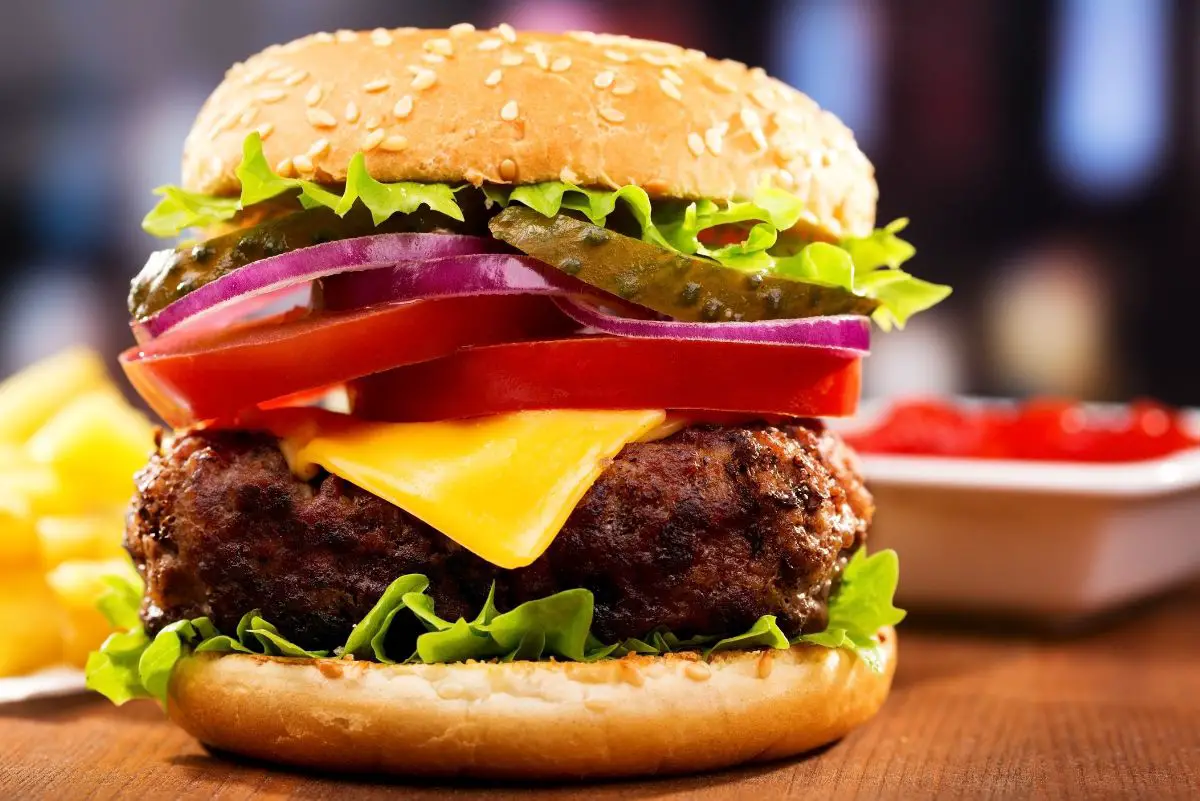 Mouthwatering Homemade Hamburgers with tomatoes, onion, cheese, and lettuce.