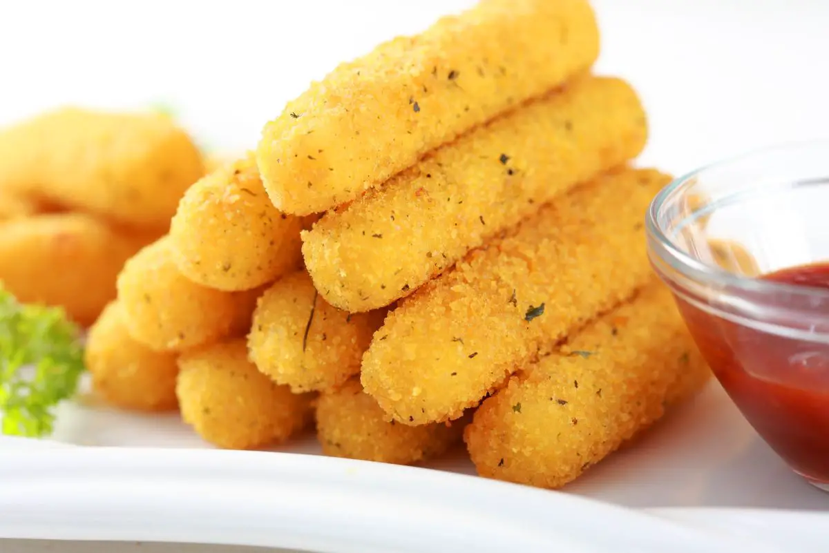 A stack of Easy Fried Mozzarella Cheese Sticks on a white plate.