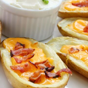 Closeup of Easy Twice Baked Potatoes with a crock of sour cream behind it.