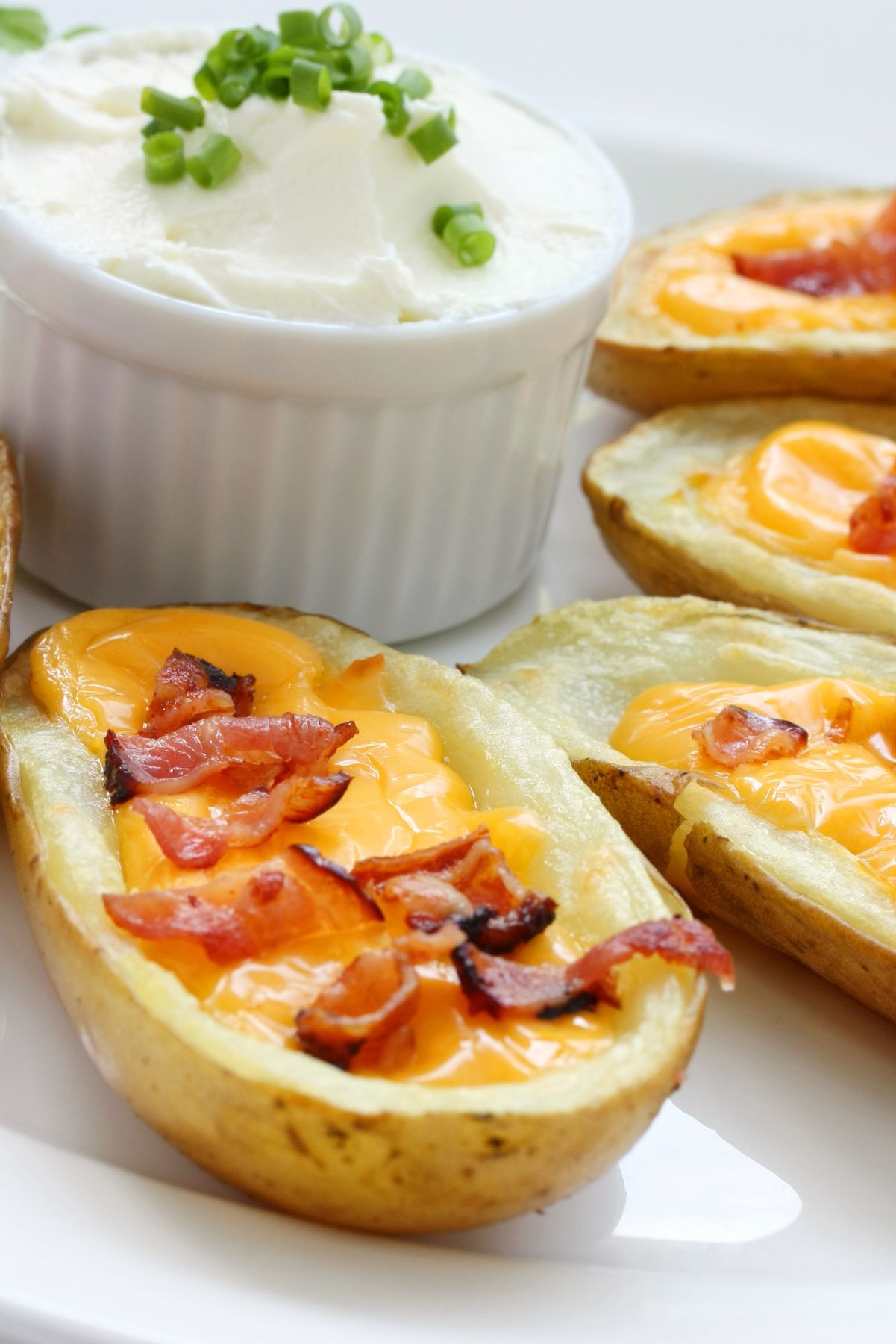 Closeup of Easy Twice Baked Potatoes with a crock of sour cream behind it.