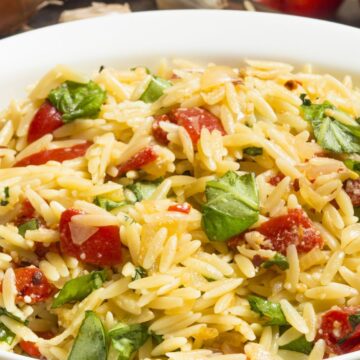 Closeup of Orzo Pasta Salad with Basil and Tomato in a white bowl.