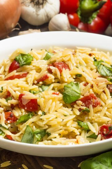 Closeup of Orzo Pasta Salad with Basil and Tomato in a white bowl.