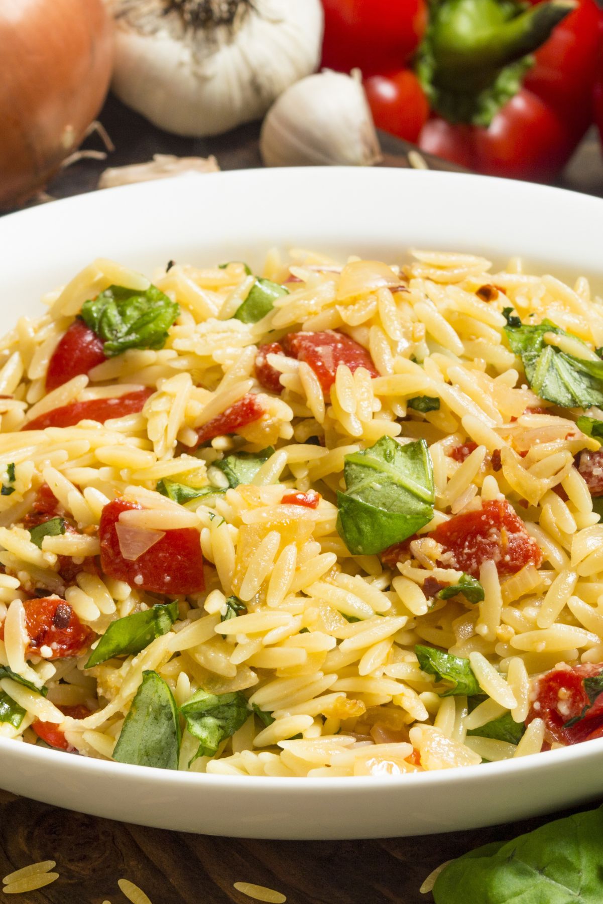 Closeup of Orzo Pasta Salad with Basil and Tomato in a white bowl.