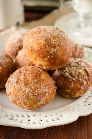 A pile of Homemade Fried Applesauce Doughnuts on a white plate.