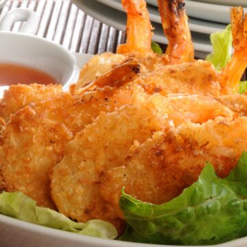 Closeup of Crispy Coconut Shrimp in Beer Batter Recipe on a bed of lettuce.