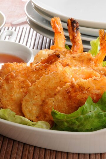 Closeup of Crispy Coconut Shrimp in Beer Batter Recipe on a bed of lettuce.