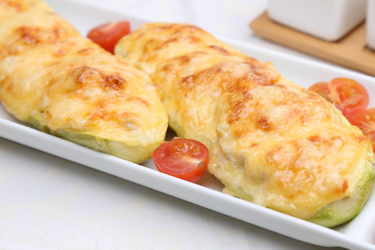 2 Grilled Garlic Parmesan Zucchinis on a rectangular, white plate with cherry tomatoes.