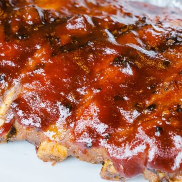 Closeup of Grilled Whisky Baby Back Ribs on a white background.