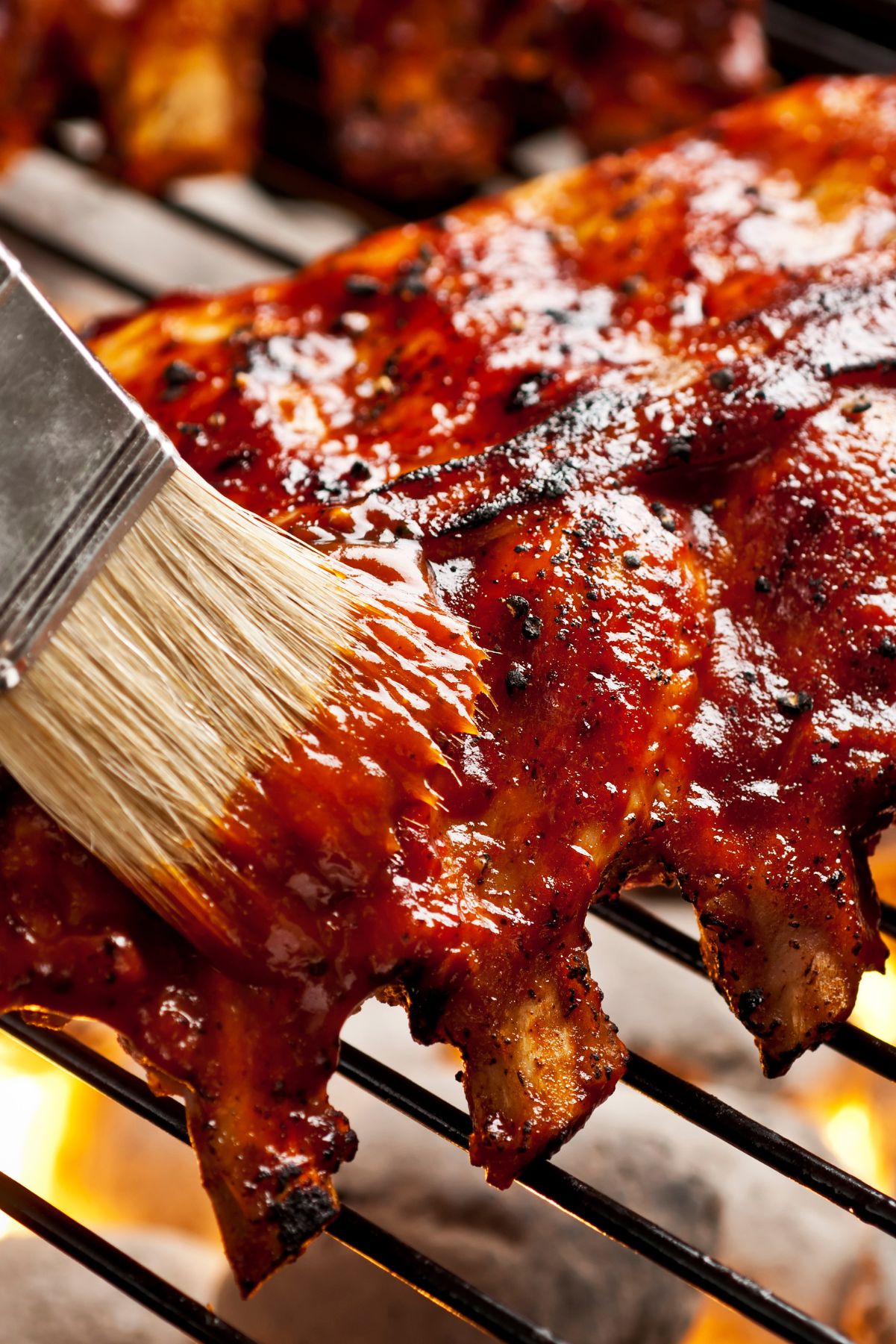 Grilled Whisky Baby Back Ribs on a grill with a grill brush.