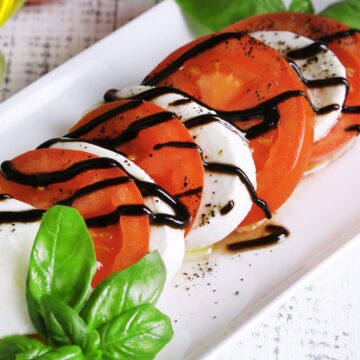 Closeup of Italian Balsamic Caprese Salad on a rectangular, white plate.