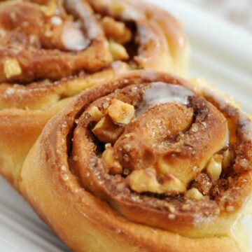 Closeup of 2 Mouthwatering Homemade Cinnamon Buns on a white surface.
