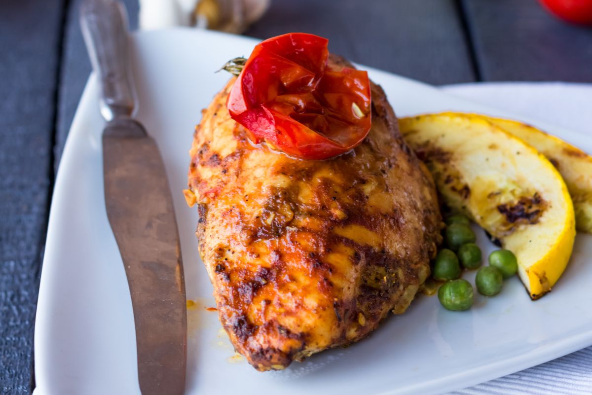 Quick and Easy Chicken Lazone on a white plate with a butter knife, and lemon slices.