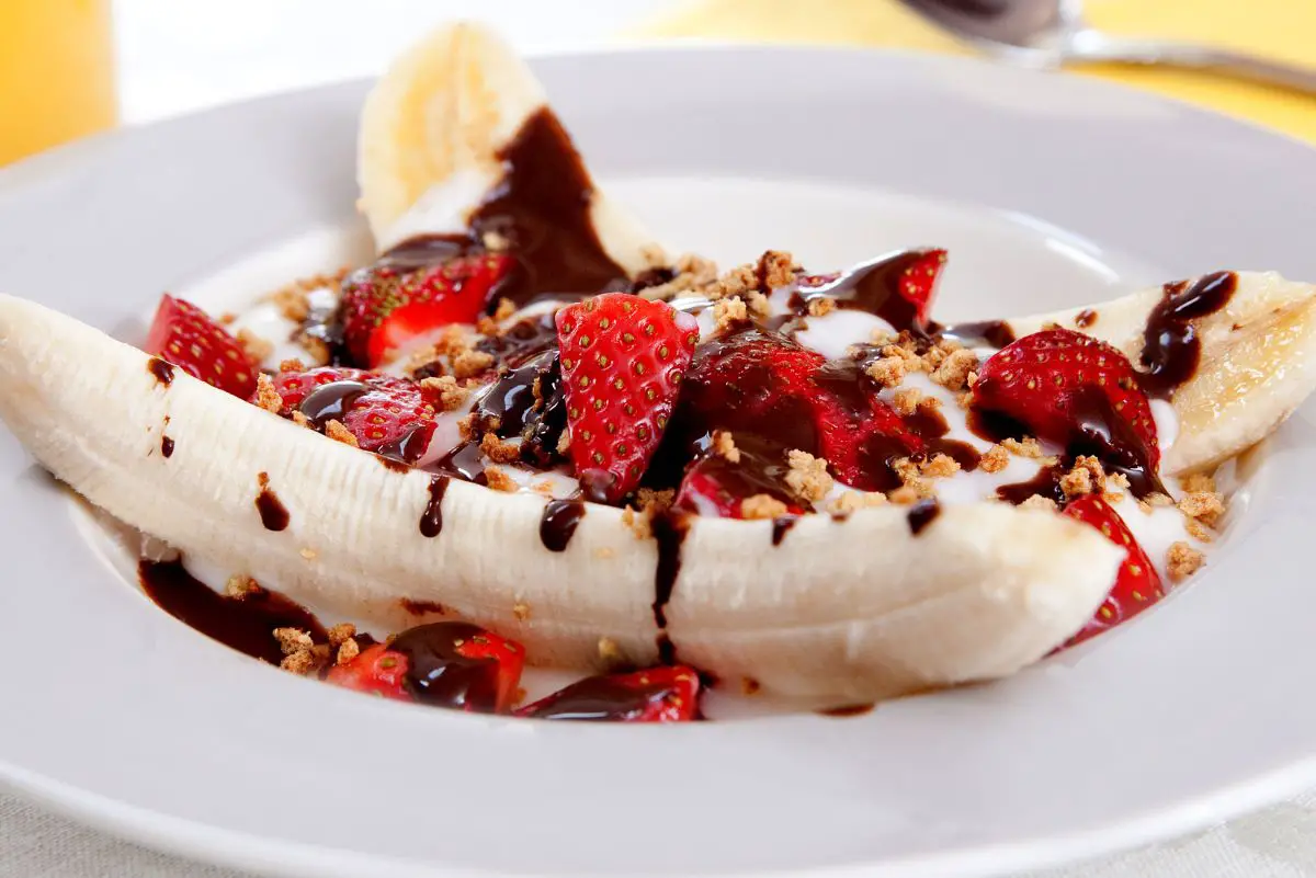 Easy Broiled Banana Split on a wide brimmed white plate.